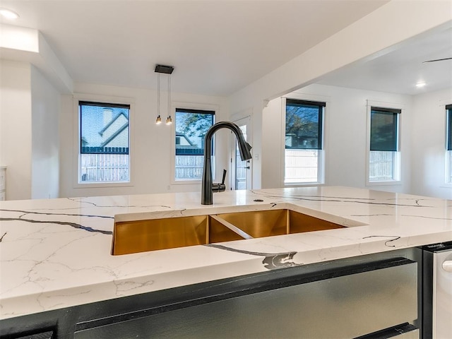 interior details featuring light stone counters, sink, and hanging light fixtures