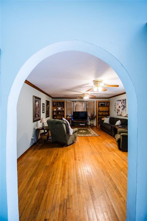 unfurnished living room featuring light wood-type flooring, ceiling fan, and crown molding