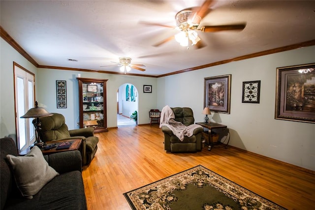 living room featuring crown molding, ceiling fan, and wood-type flooring