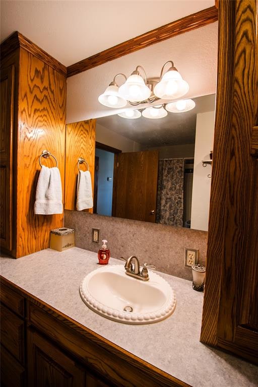 bathroom with a shower with shower curtain, vanity, and crown molding