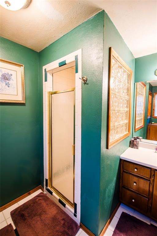 bathroom with tile patterned floors, a shower with door, and vanity