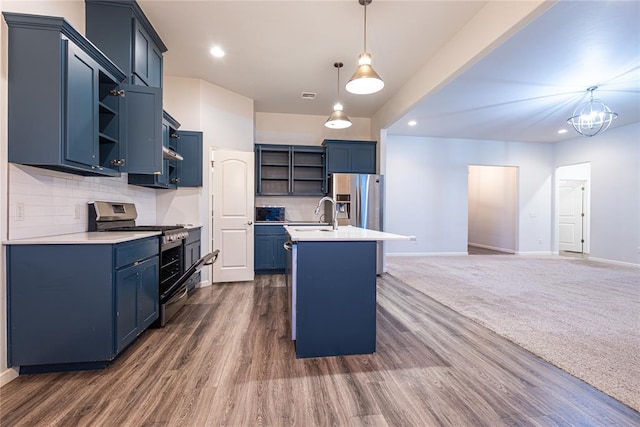 kitchen featuring pendant lighting, blue cabinetry, backsplash, stainless steel appliances, and a center island with sink