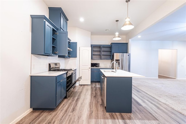 kitchen with pendant lighting, sink, stainless steel appliances, an island with sink, and blue cabinets