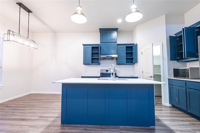 kitchen featuring pendant lighting, sink, a kitchen island with sink, and tasteful backsplash