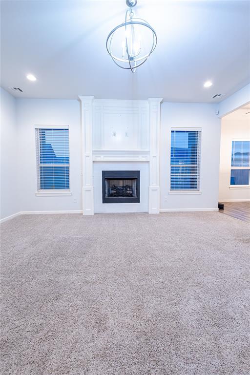 unfurnished living room with carpet floors and a chandelier