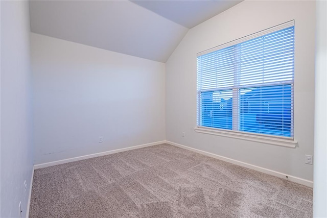 empty room with vaulted ceiling and carpet flooring