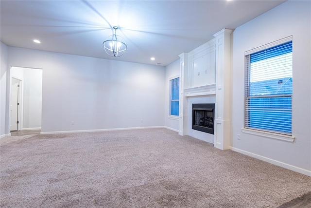 unfurnished living room featuring an inviting chandelier, a fireplace, and carpet floors