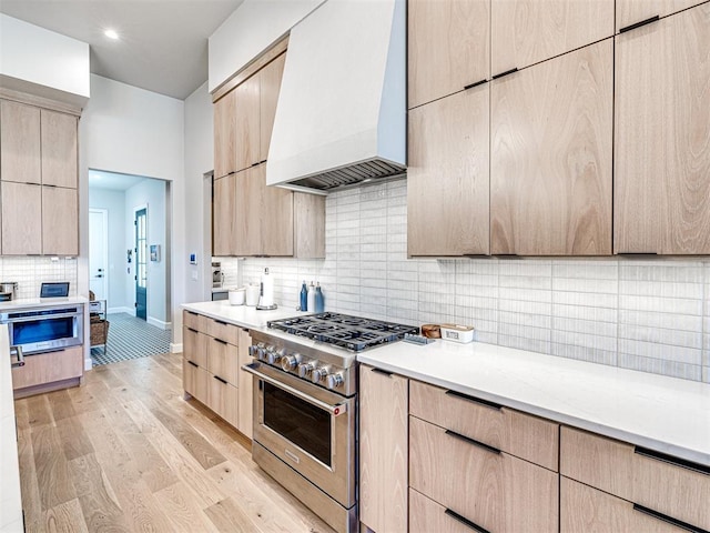 kitchen featuring light brown cabinetry, light hardwood / wood-style flooring, appliances with stainless steel finishes, and custom exhaust hood