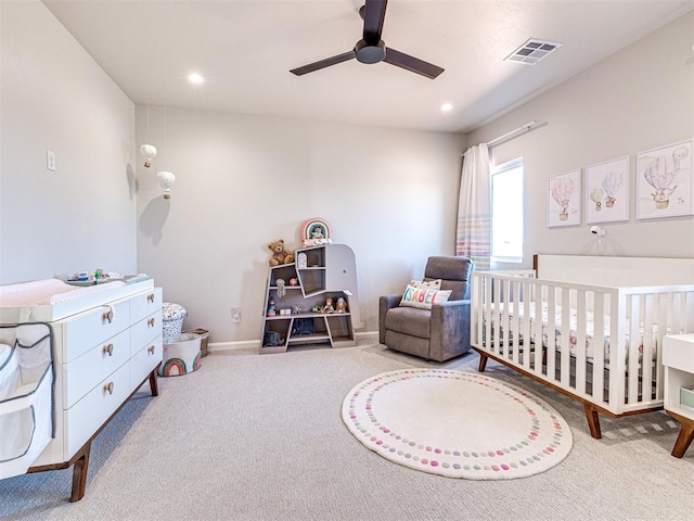 carpeted bedroom featuring ceiling fan and a crib