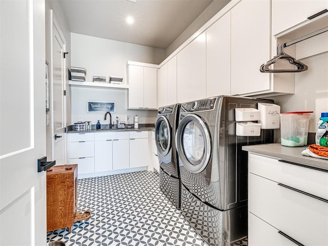 laundry area featuring washing machine and clothes dryer, sink, and cabinets