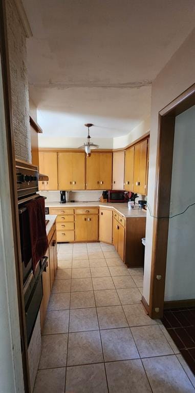 kitchen with stainless steel oven, light brown cabinets, light tile patterned flooring, and ceiling fan