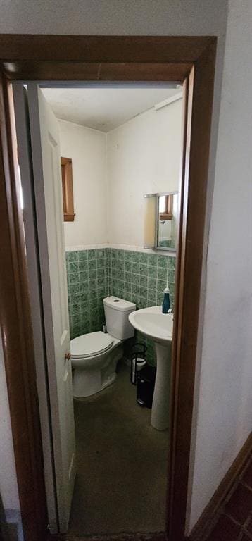 bathroom with toilet and tile walls