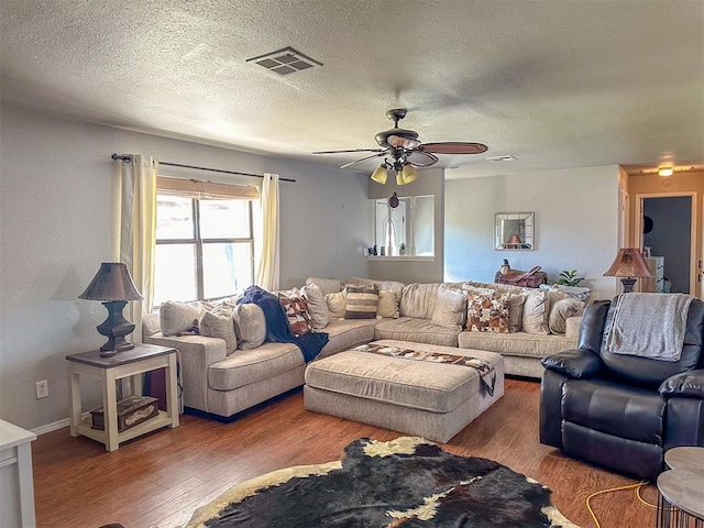 living room featuring a textured ceiling, hardwood / wood-style floors, and ceiling fan