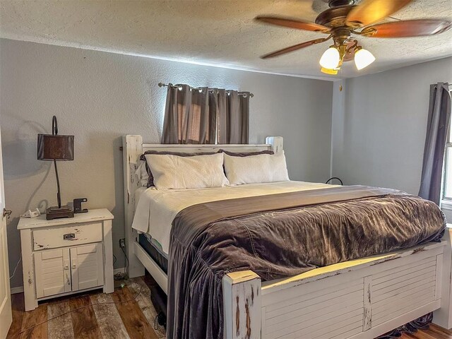 bedroom featuring dark hardwood / wood-style flooring, ceiling fan, and a textured ceiling