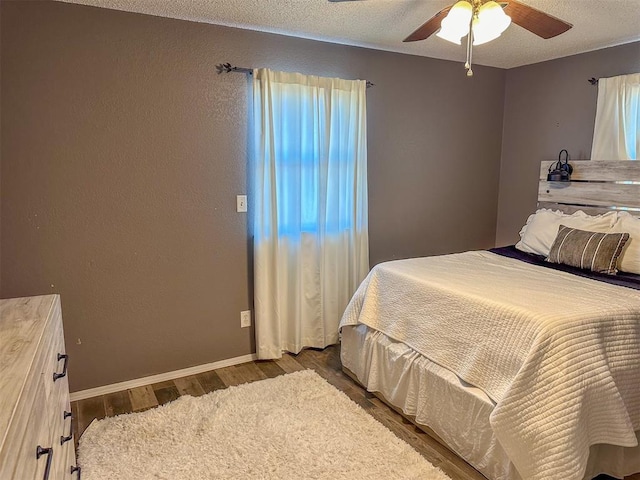 bedroom featuring ceiling fan, dark hardwood / wood-style flooring, and a textured ceiling