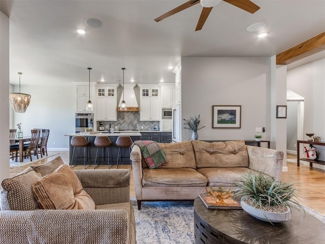 living room with ceiling fan with notable chandelier and light wood-type flooring