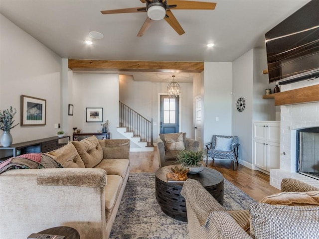 living room with hardwood / wood-style floors, ceiling fan with notable chandelier, and a fireplace