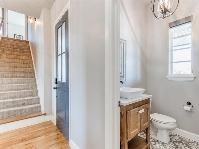 bathroom with hardwood / wood-style floors, vanity, toilet, and a chandelier