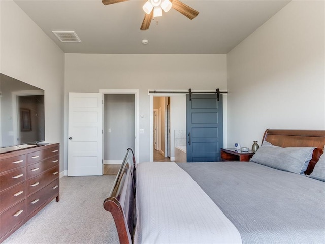 bedroom featuring a barn door, ceiling fan, and light carpet