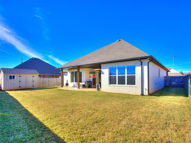 rear view of house featuring a storage unit, a yard, and a patio