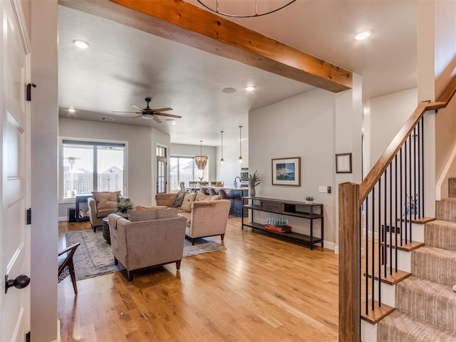 living room featuring beamed ceiling, light wood-type flooring, and ceiling fan