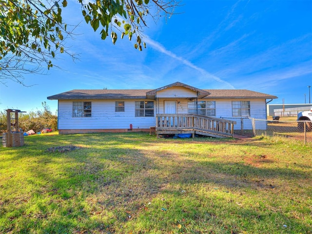 rear view of property featuring a wooden deck and a lawn