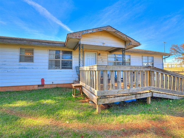 back of property with a deck and a yard