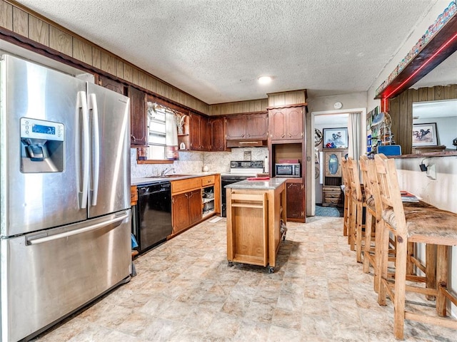 kitchen with decorative backsplash, a kitchen island, stainless steel appliances, and a textured ceiling