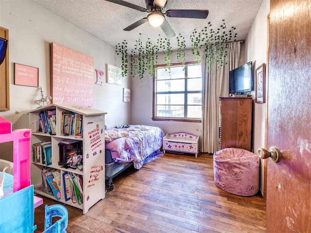 bedroom with a textured ceiling, hardwood / wood-style flooring, and ceiling fan