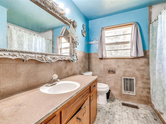 bathroom featuring tile patterned flooring, vanity, toilet, and tile walls