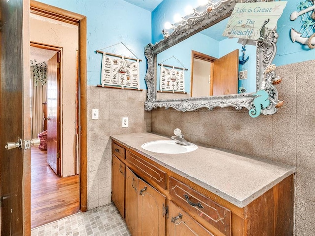 bathroom with hardwood / wood-style flooring, vanity, and tile walls