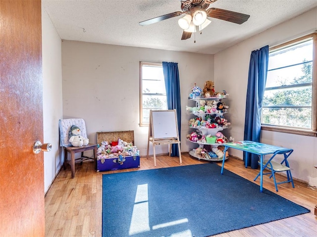 rec room with hardwood / wood-style flooring, ceiling fan, and a textured ceiling