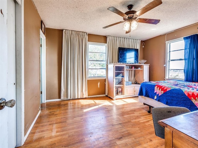 bedroom with ceiling fan, a textured ceiling, and light hardwood / wood-style flooring