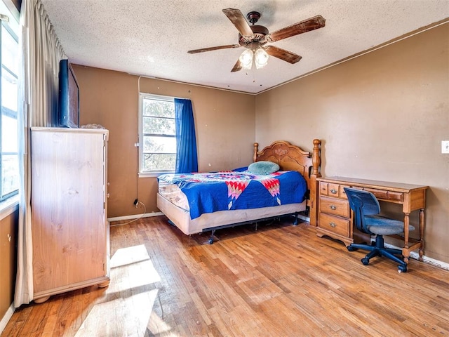 bedroom with ceiling fan, wood-type flooring, and a textured ceiling