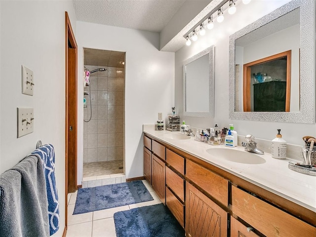 bathroom with tiled shower, vanity, a textured ceiling, and tile patterned floors