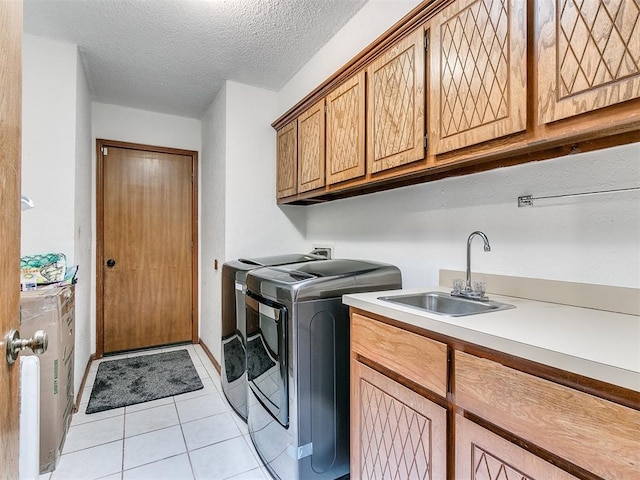 washroom featuring cabinets, sink, independent washer and dryer, a textured ceiling, and light tile patterned floors