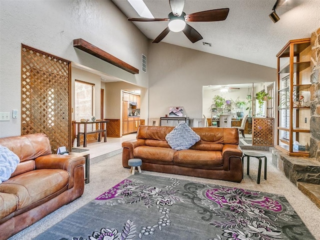 carpeted living room with a skylight, ceiling fan, high vaulted ceiling, and a textured ceiling