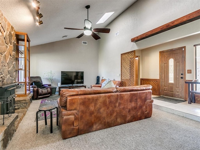 living room featuring a wood stove, ceiling fan, a healthy amount of sunlight, light colored carpet, and a textured ceiling