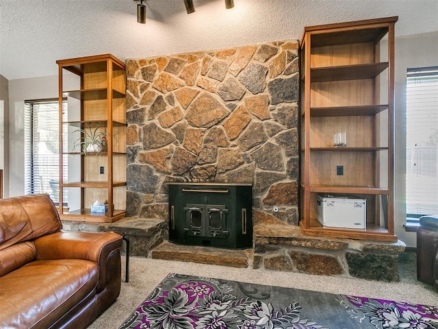 living room with a wood stove, carpet floors, and a textured ceiling