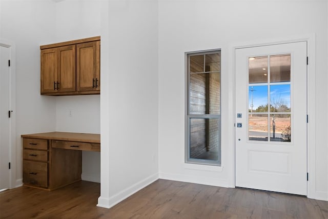 doorway featuring built in study area, light wood-style flooring, and baseboards