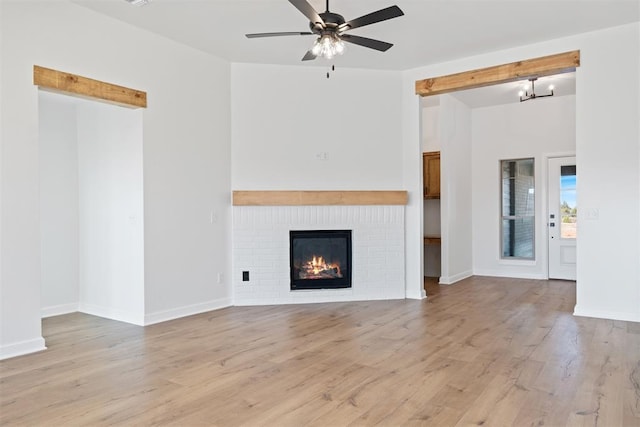 unfurnished living room featuring light wood-style floors, ceiling fan, a fireplace, and baseboards