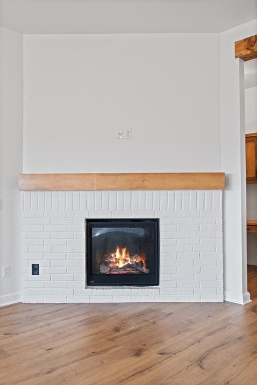 details with a brick fireplace, wood finished floors, and baseboards