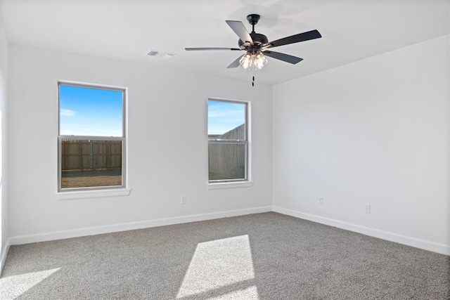 carpeted spare room featuring ceiling fan, visible vents, and baseboards