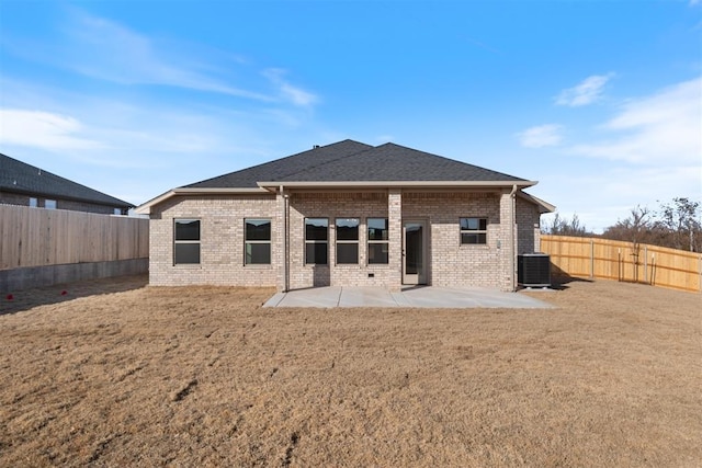 rear view of house featuring brick siding, a yard, roof with shingles, a patio area, and a fenced backyard