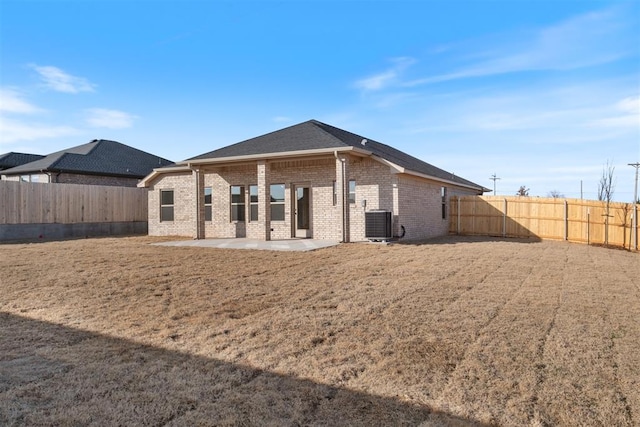 rear view of property featuring a fenced backyard, brick siding, a patio, and central AC unit