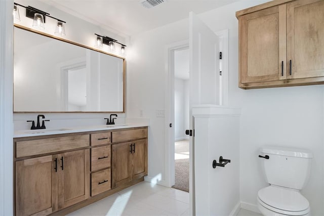 bathroom featuring visible vents, a sink, toilet, and double vanity