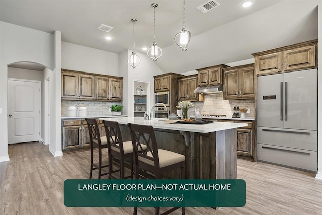 kitchen with stainless steel appliances, backsplash, pendant lighting, vaulted ceiling, and a center island with sink