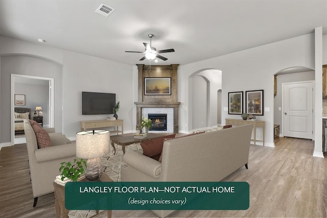 living room featuring ceiling fan, light wood-type flooring, and a fireplace