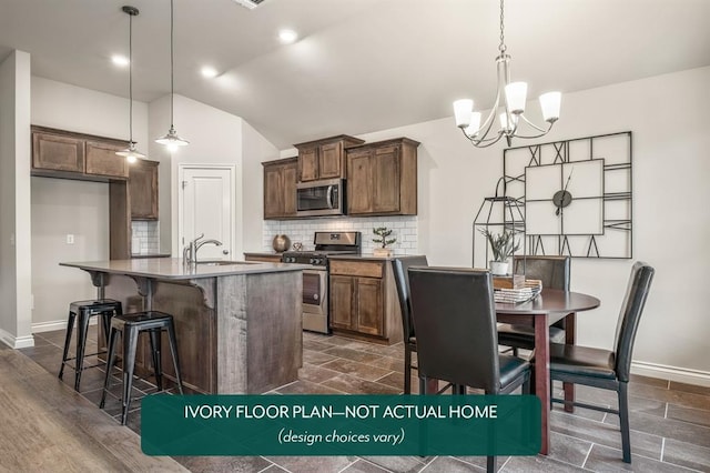 kitchen featuring hanging light fixtures, an island with sink, appliances with stainless steel finishes, and vaulted ceiling