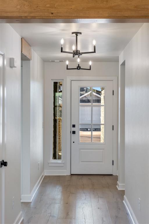 doorway featuring light hardwood / wood-style flooring, a wealth of natural light, and an inviting chandelier